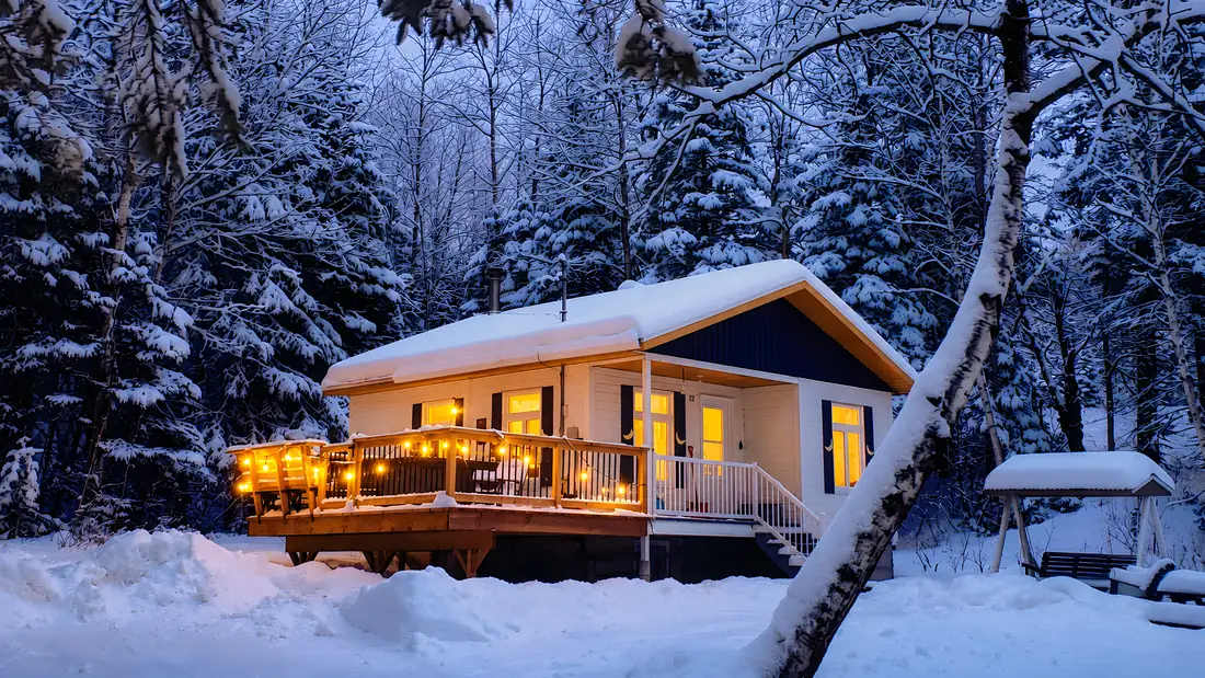 Un chalet des Refuges des Monts en soirée d'hiver, terrasse illuminée