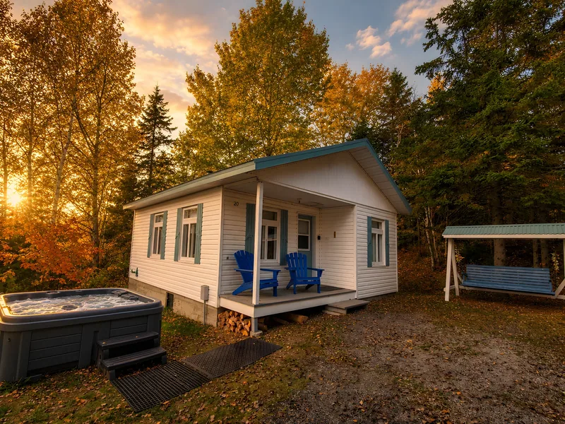 Le Grand Chêne — Cottage and outdoor hot tub surrounded by trees at sunset